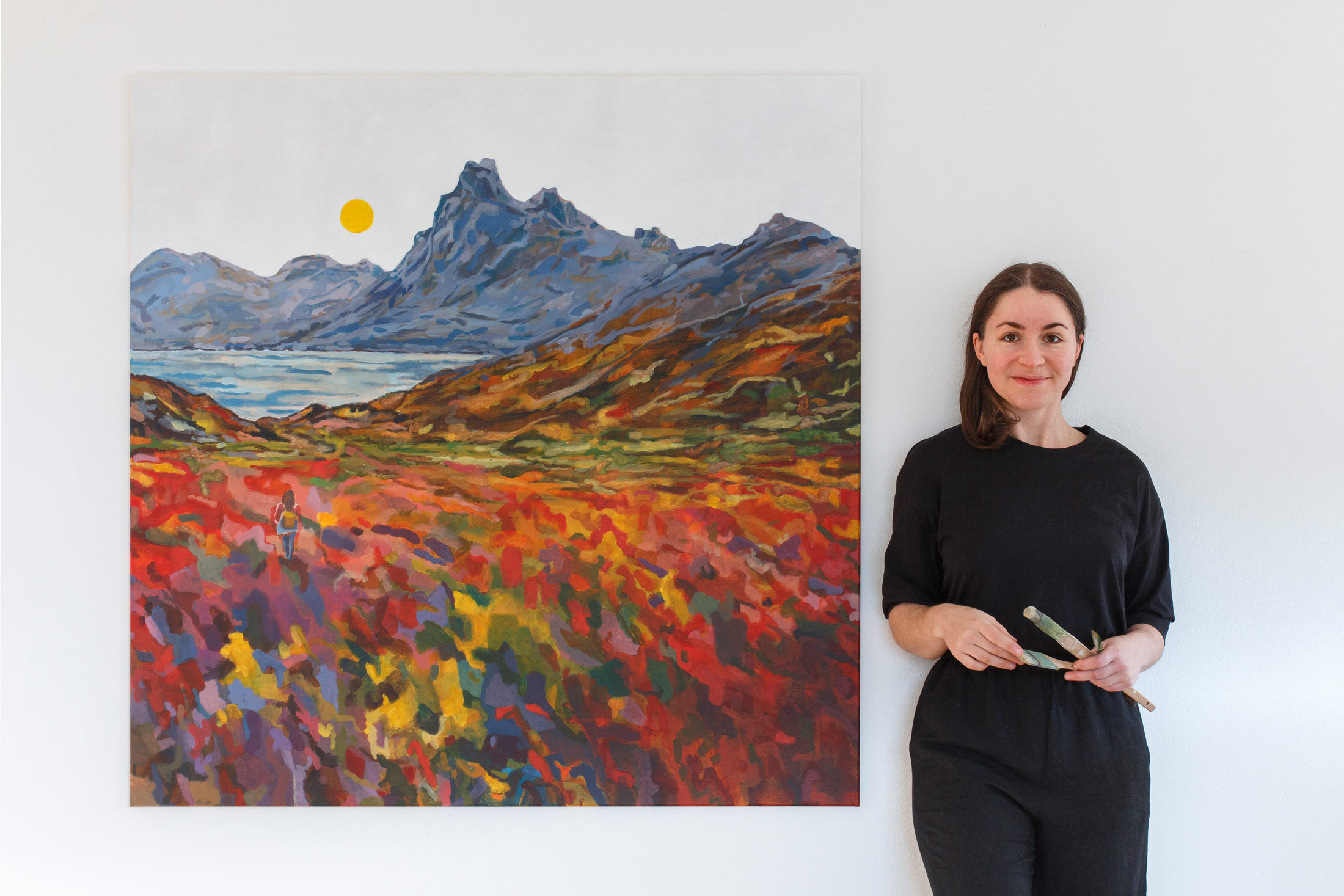 Die Künstlerin und Malerin Anja Dommel steht neben einem XXL Gemälde vom Eystrahorn in Island als Sehnsuchtsort in Acryl