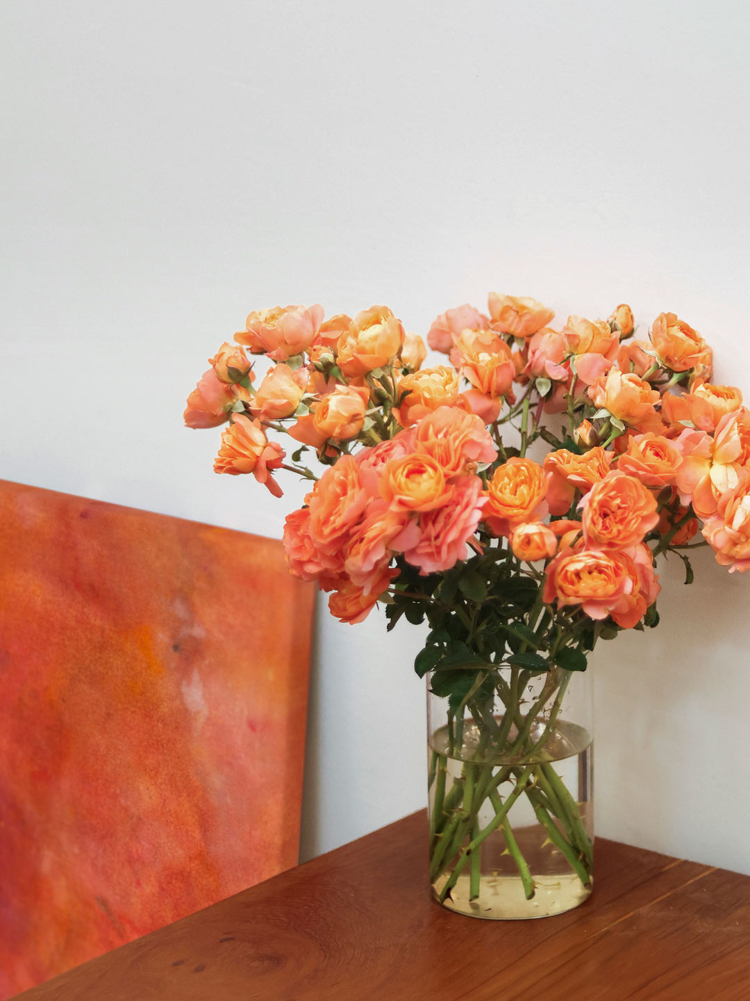Abstrakte Kunst in Rosé Weinfarben mit Rosen auf Eichentisch