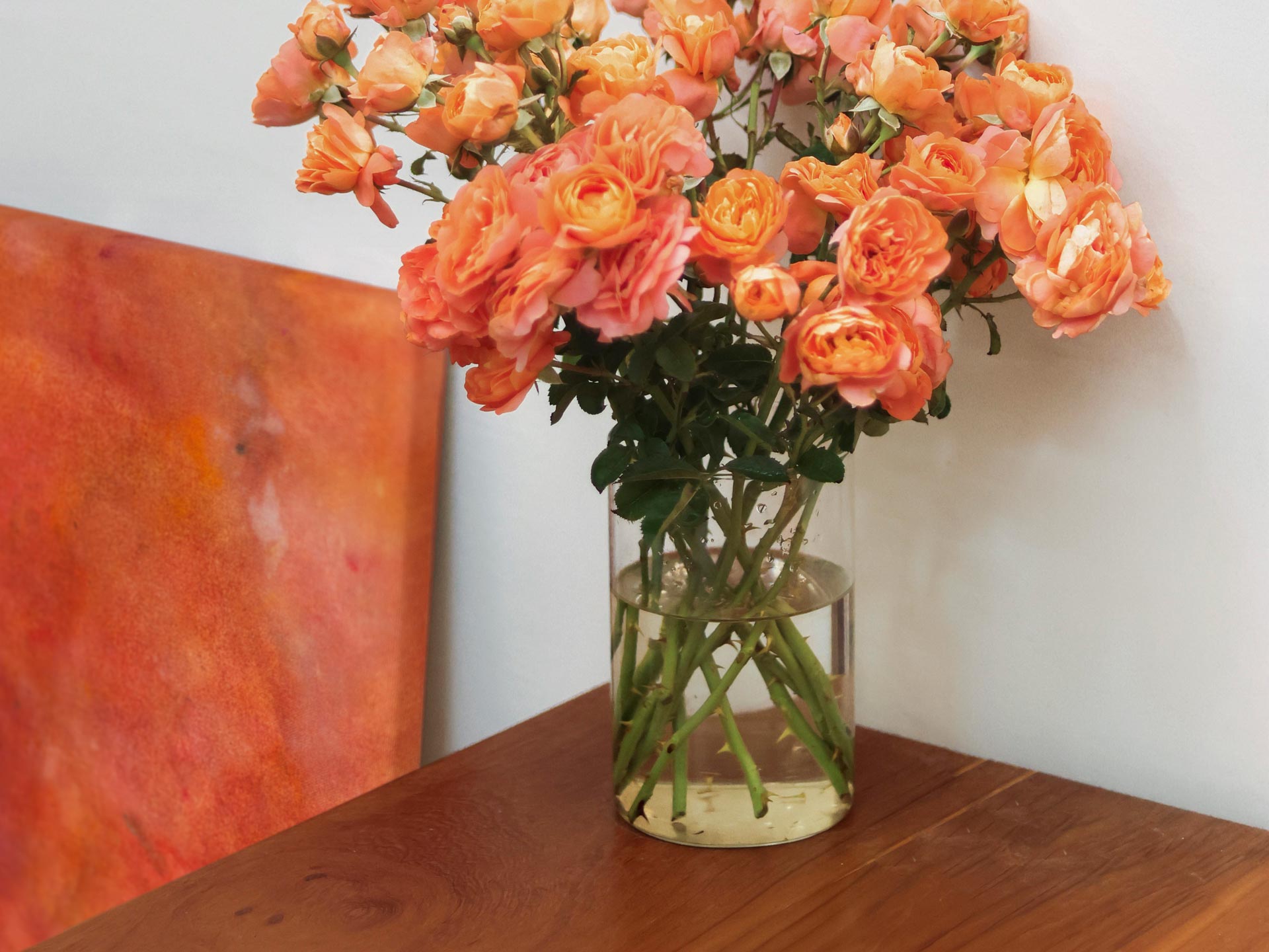 Abstrakte Kunst in Rosé Weinfarben mit Rosen auf Eichentisch